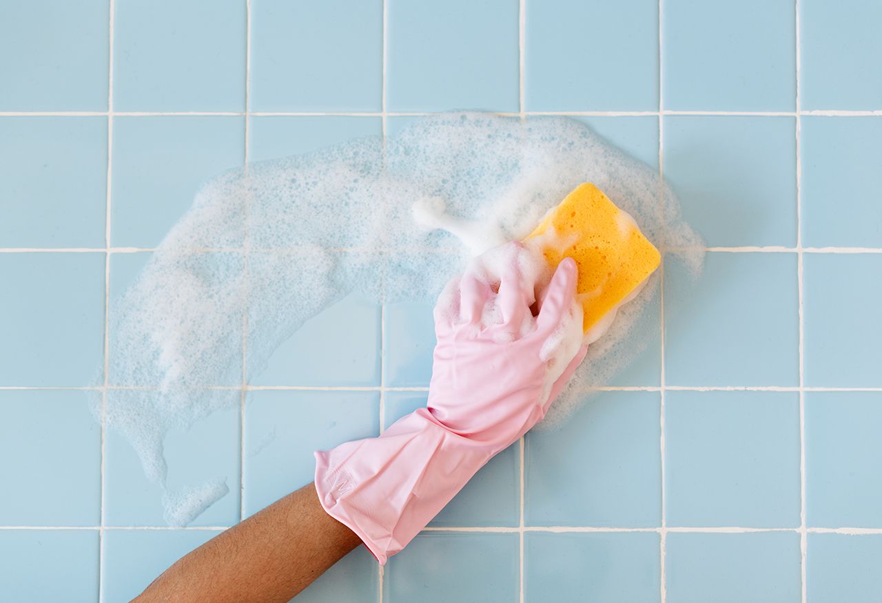 woman cleaning blue tile bathroom
