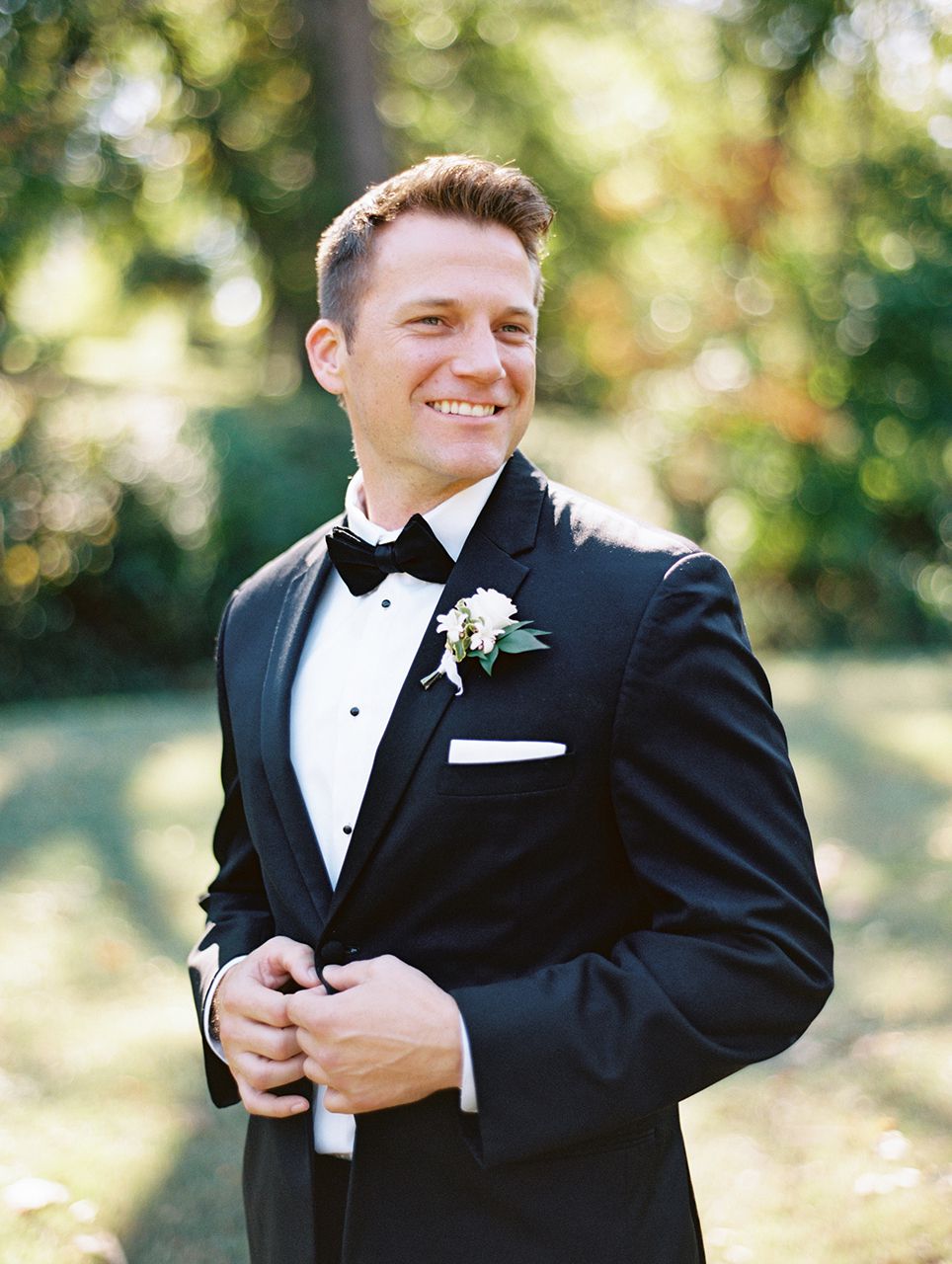 groom posing in black tuxedo outdoors