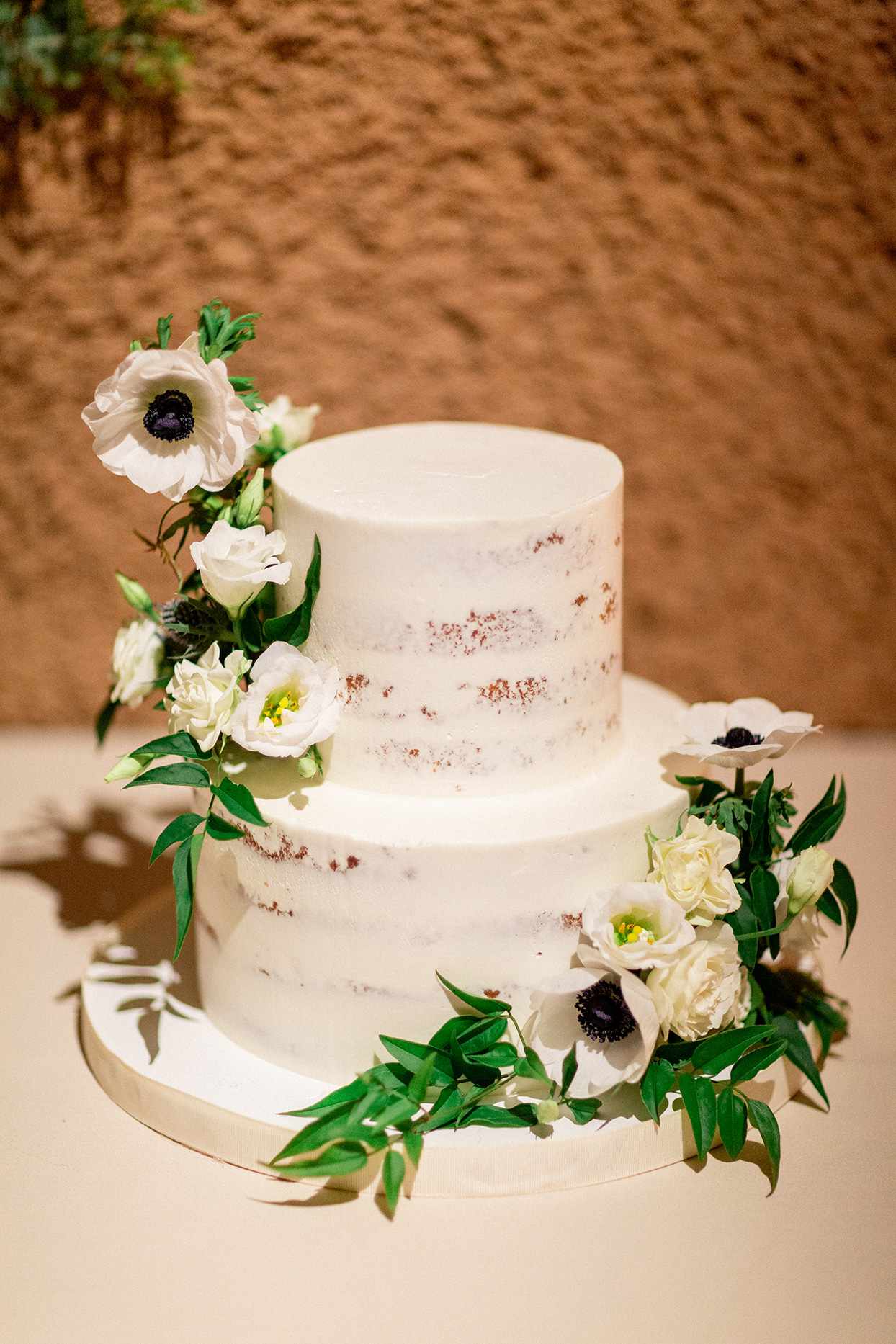 simple almost naked wedding cake with white flowers