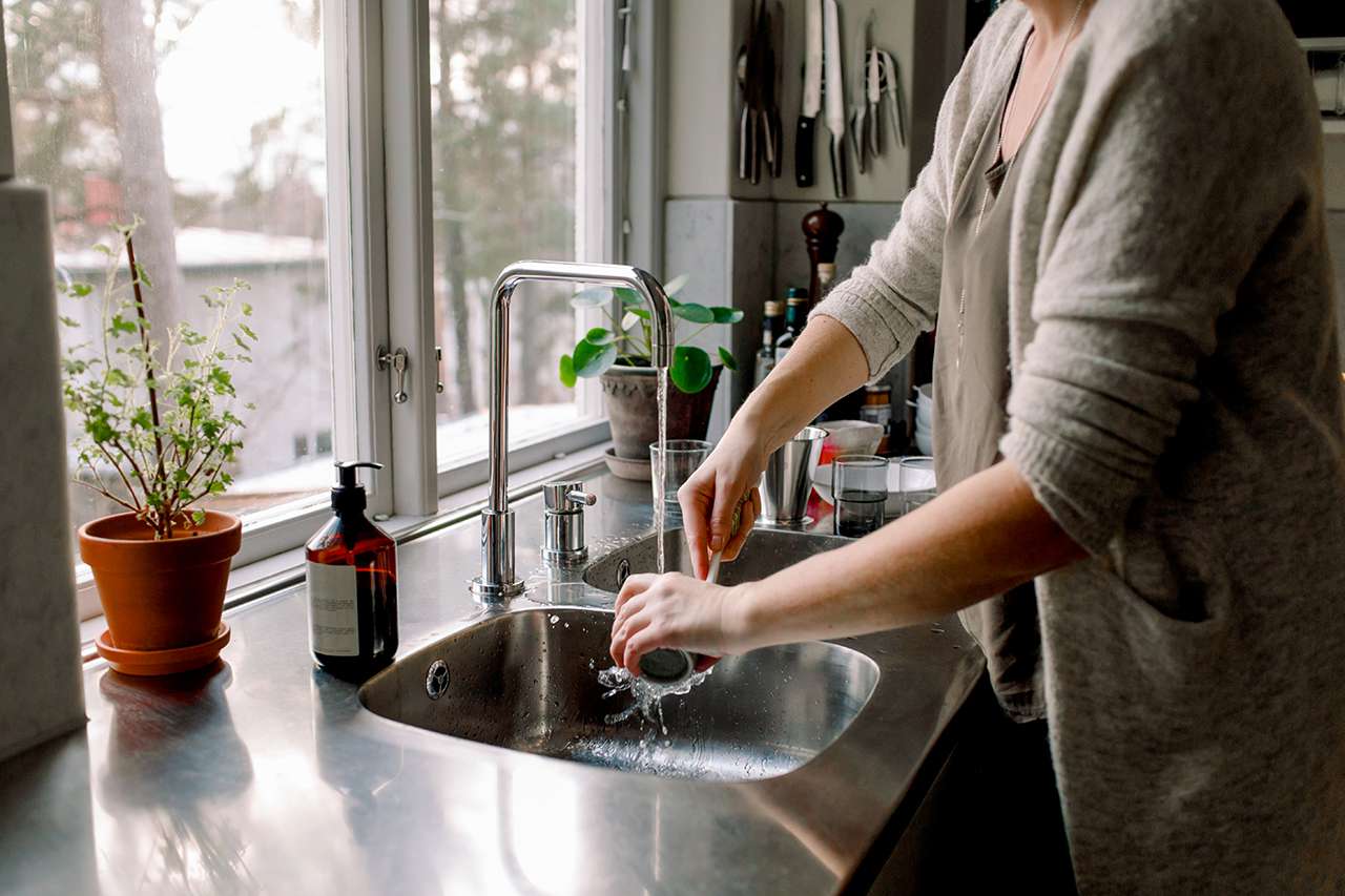 woman washing dishes with brush