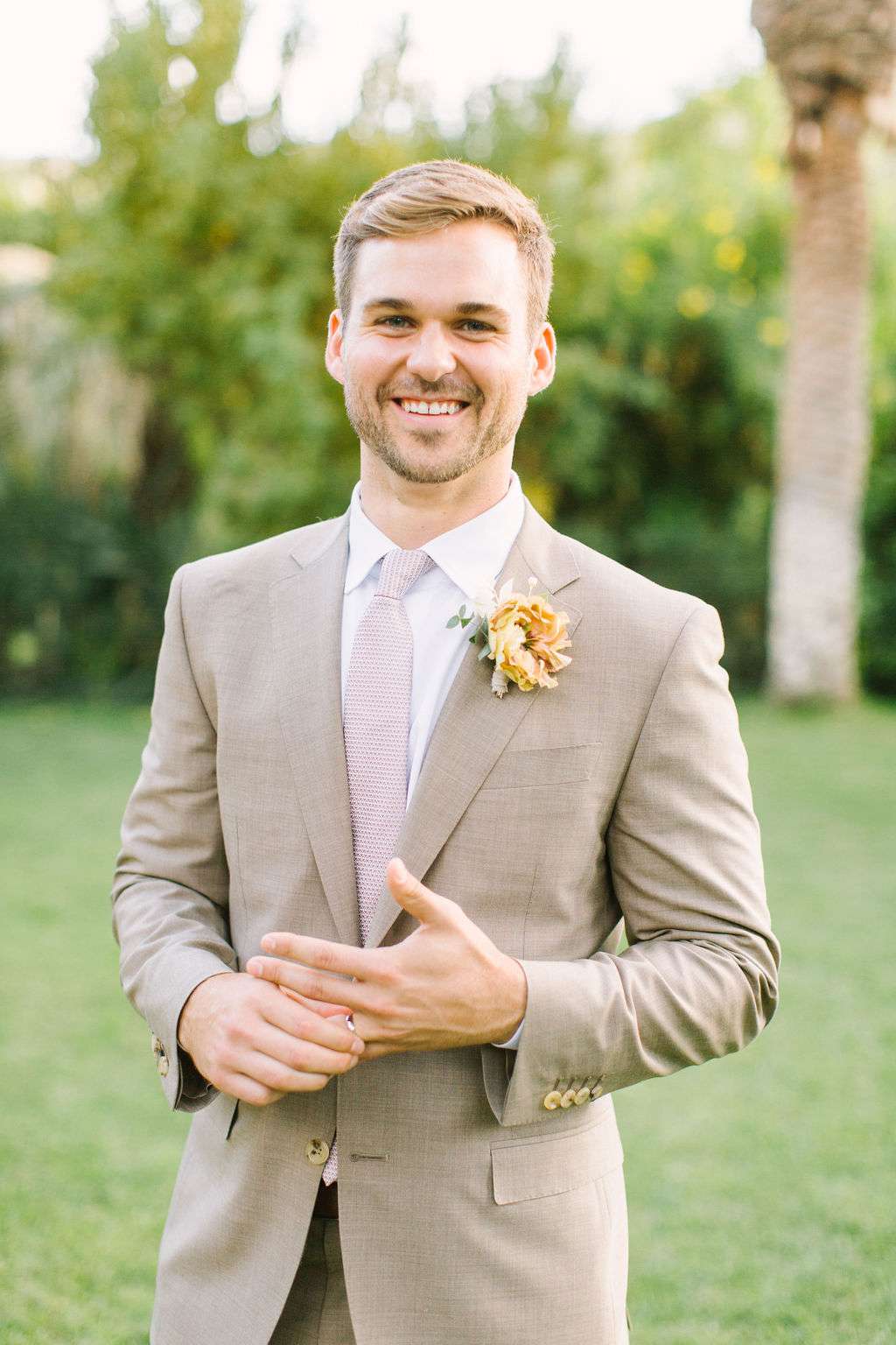 groom in light brown suit with pastel pink tie
