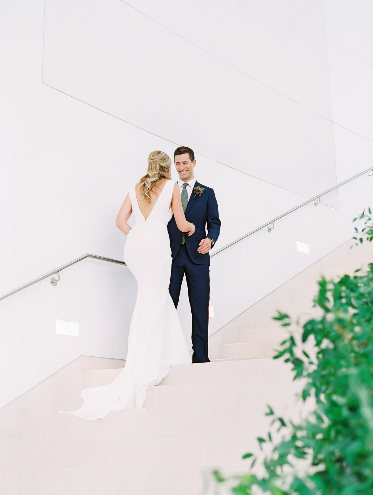 groom smiles at bride during first look on staircase