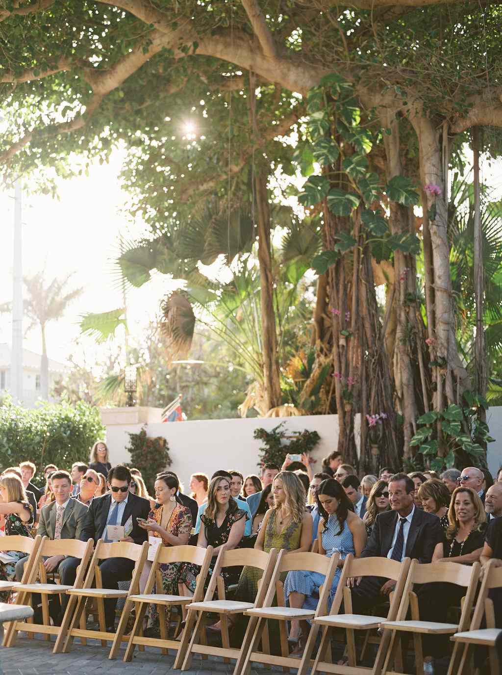 wedding guests sitting in wooden chairs for backyard wedding