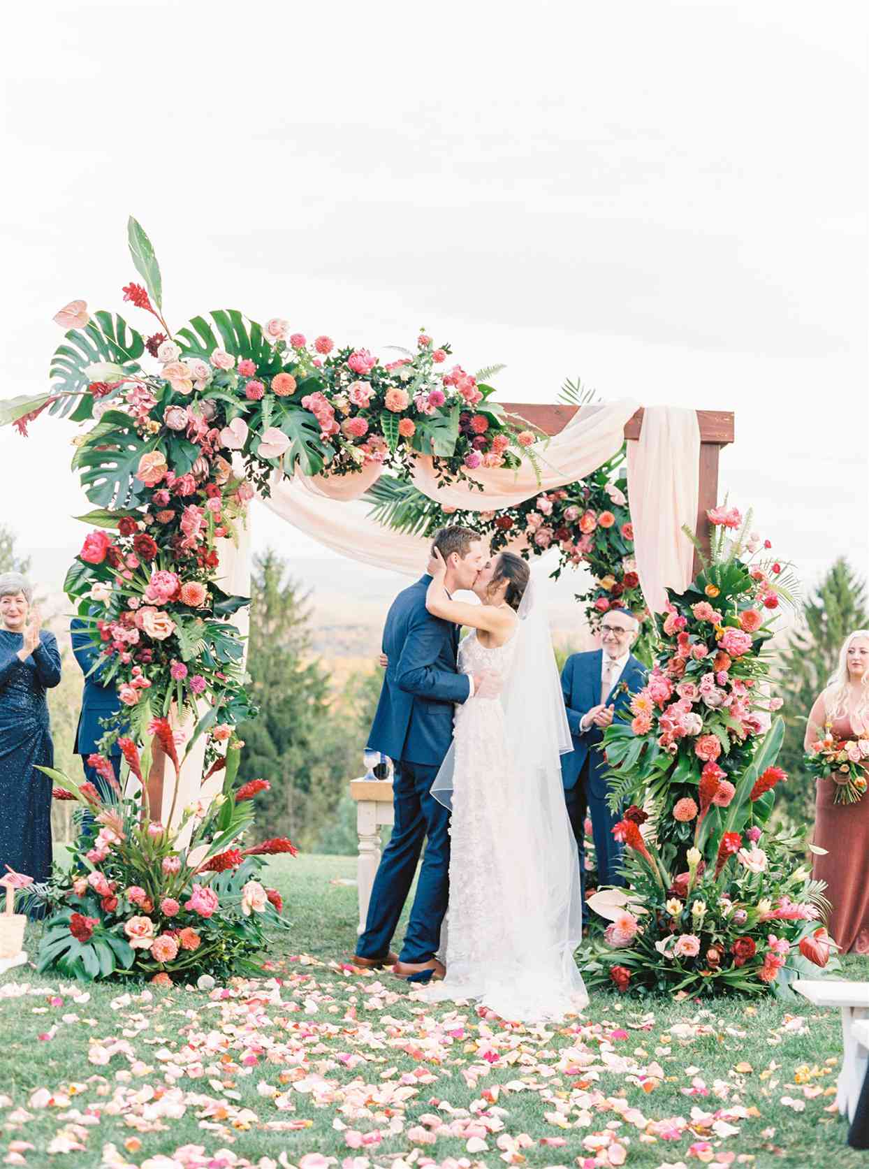 couple kissing under floral arch at outdoor ceremony