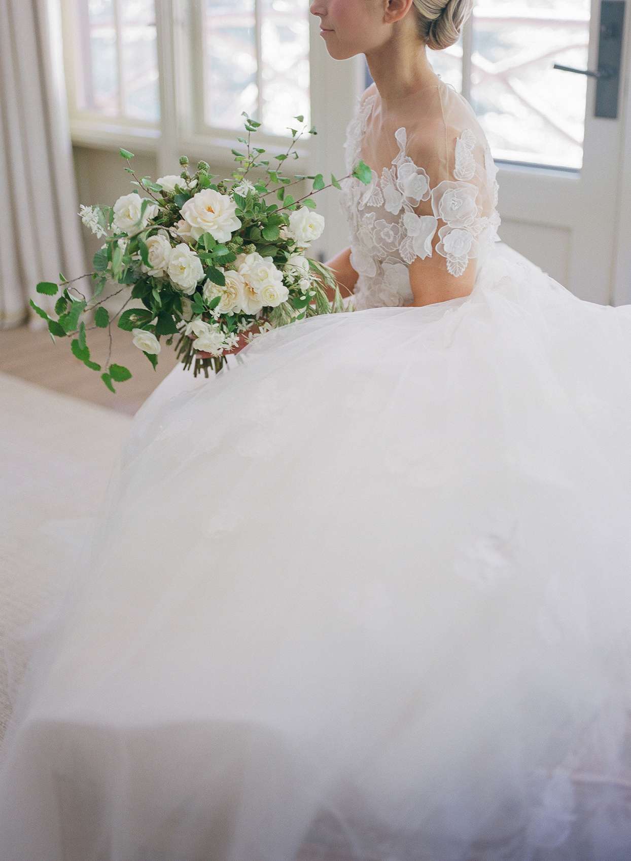 bride in fluffy dress sitting with bouquet