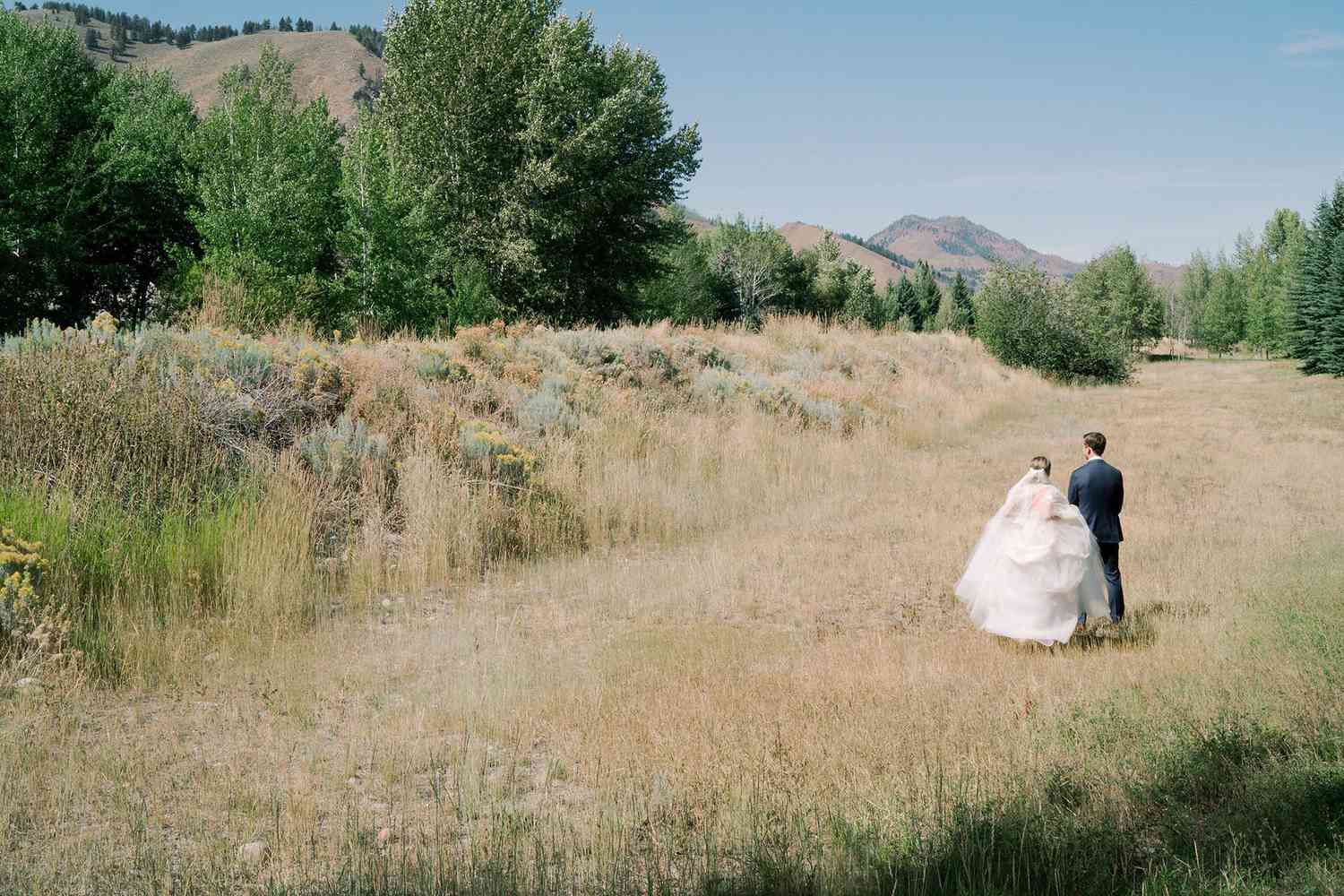 wedding couple first look in field with mountain view
