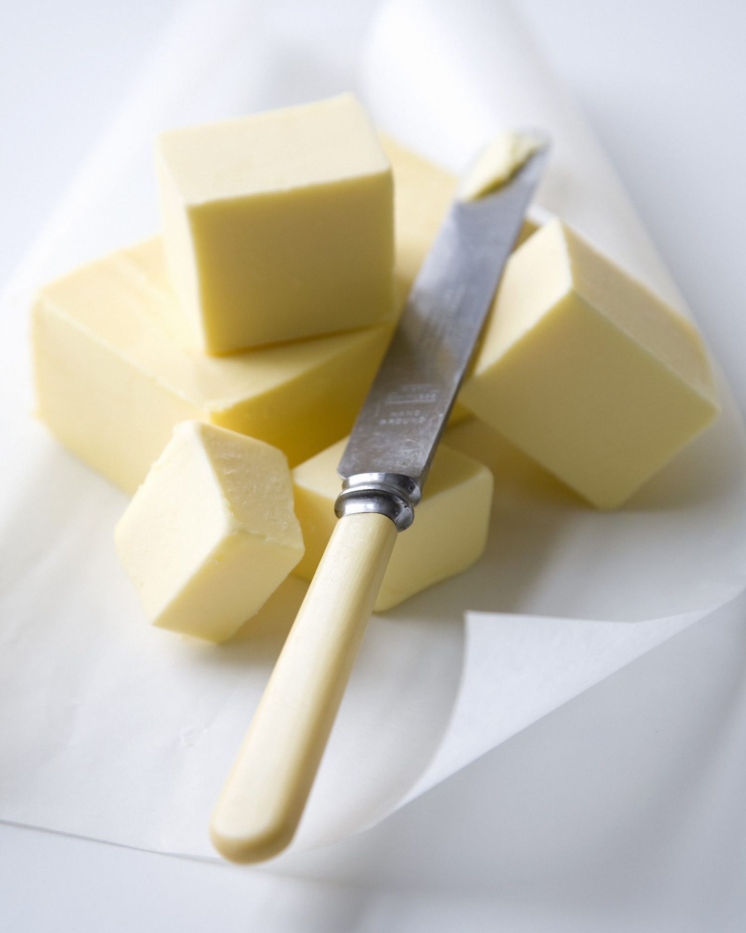 Blocks of butter and butter knife on parchment paper