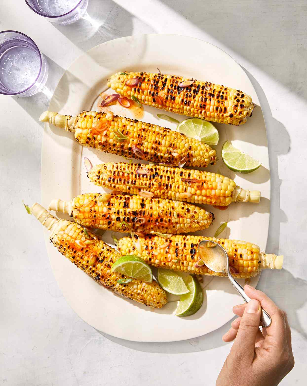 grilled corn with fish sauce and scallions served with lime wedges