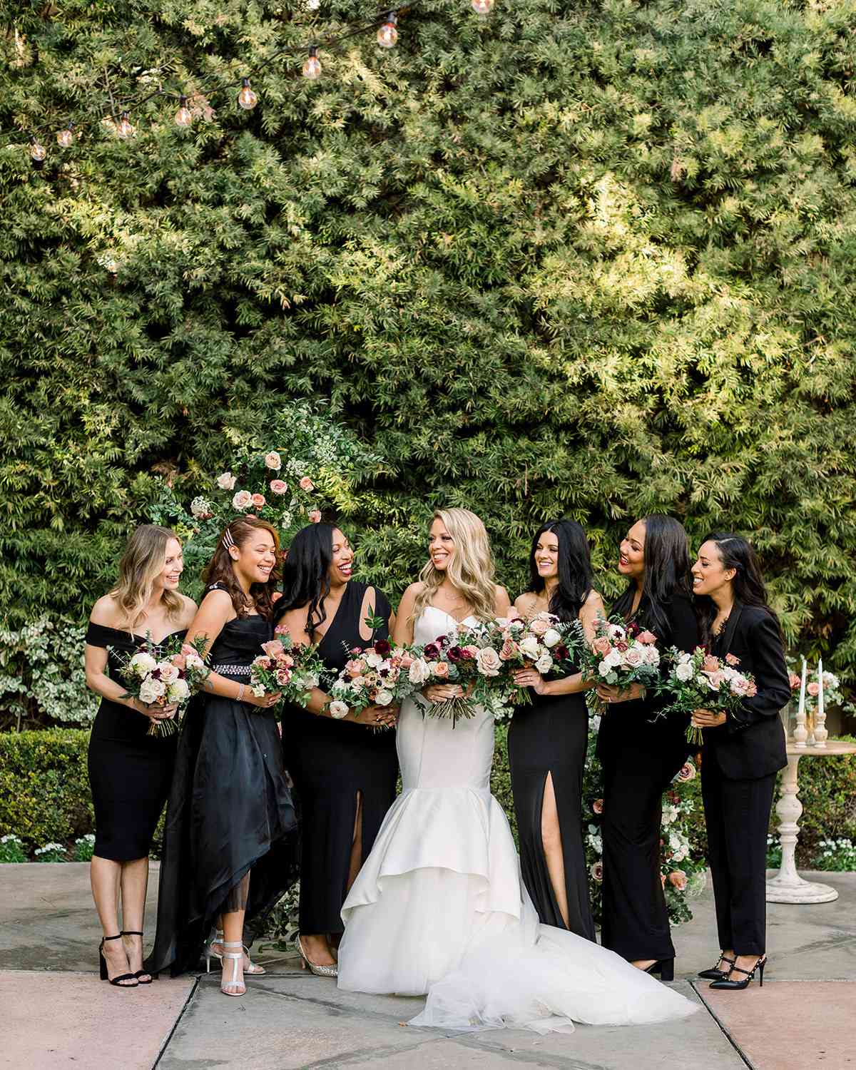 bride and bridesmaids in black against greenery wall