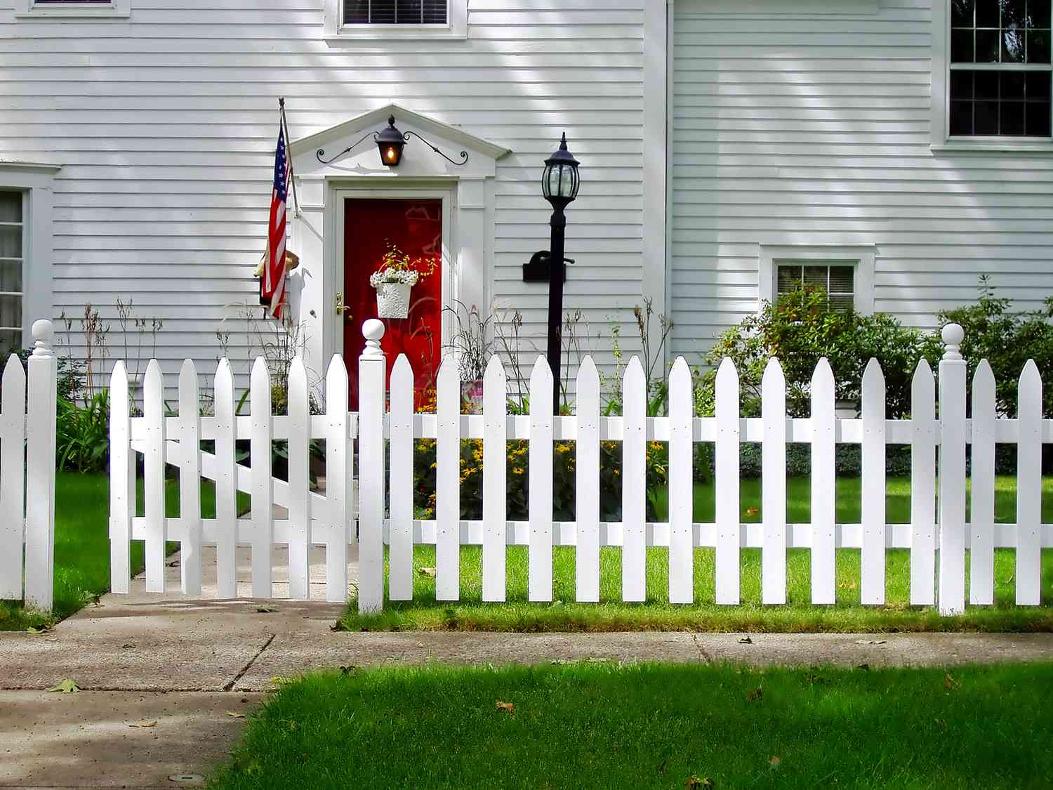 white picket fence around white house with red front door
