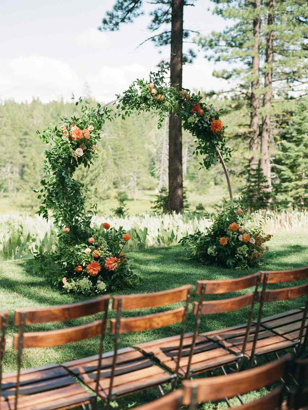 minimalistic wedding ceremony arch adorned with orange flowers and greenery