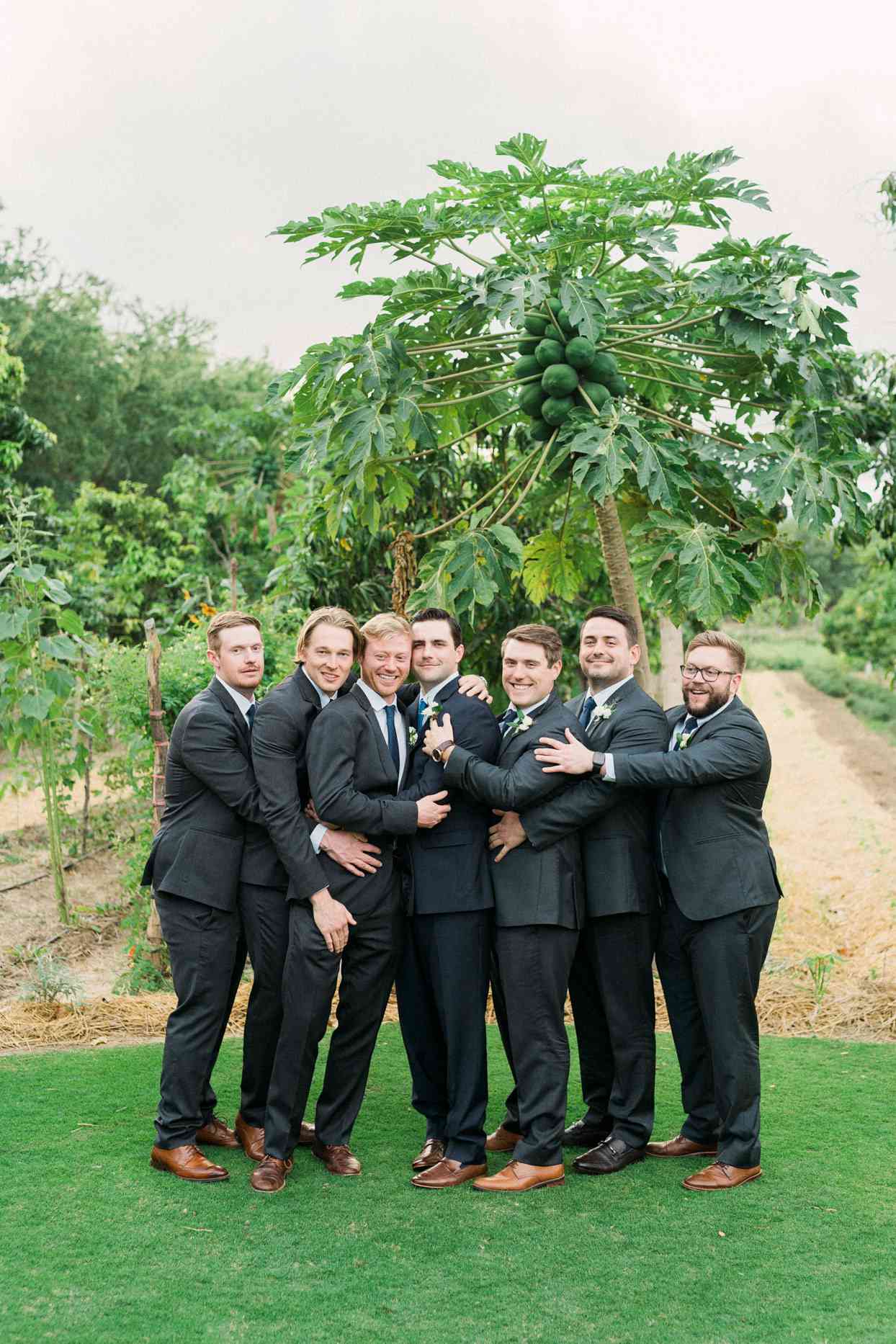 groomsmen posing in black suits and brown shoes