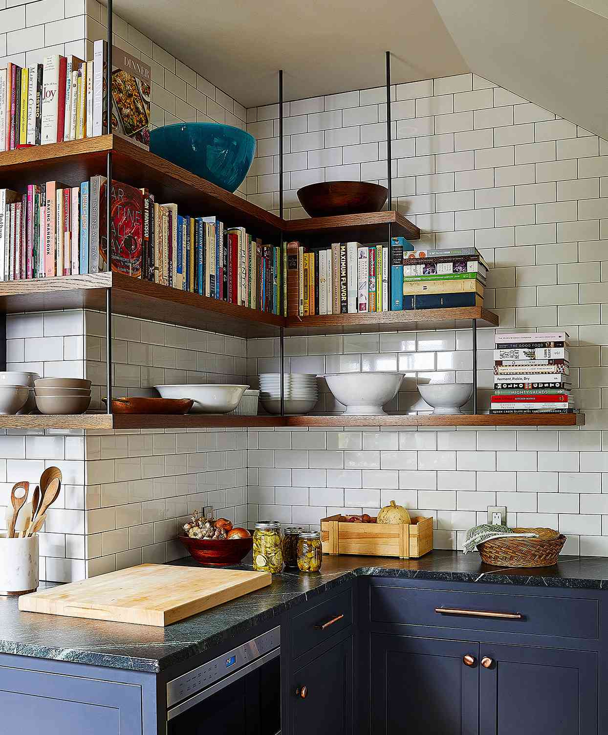 kitchen corner with blue cabinets and hanging exposed shelves with cookbooks and dishes
