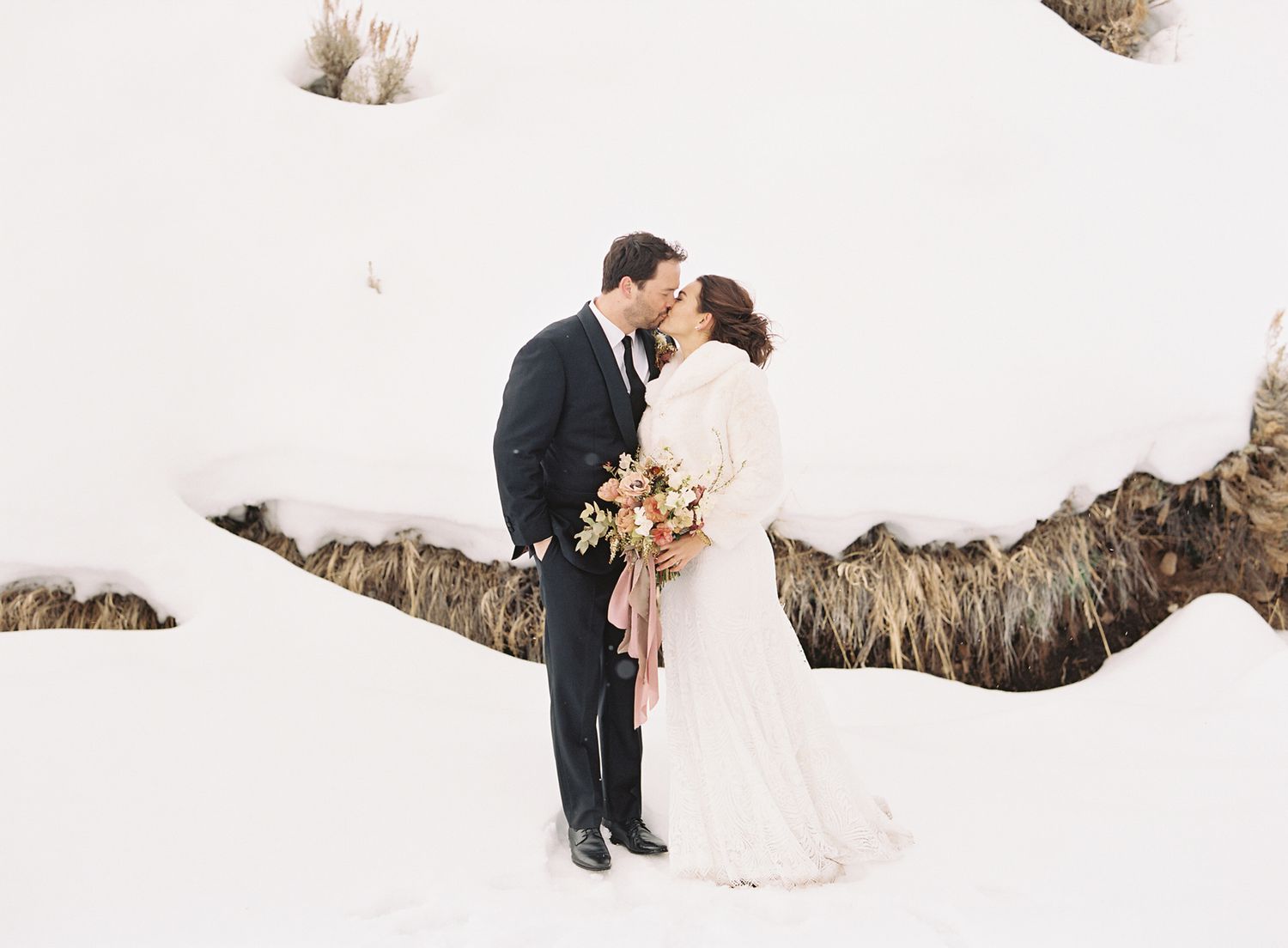 bride and groom share a kiss outside in the snow