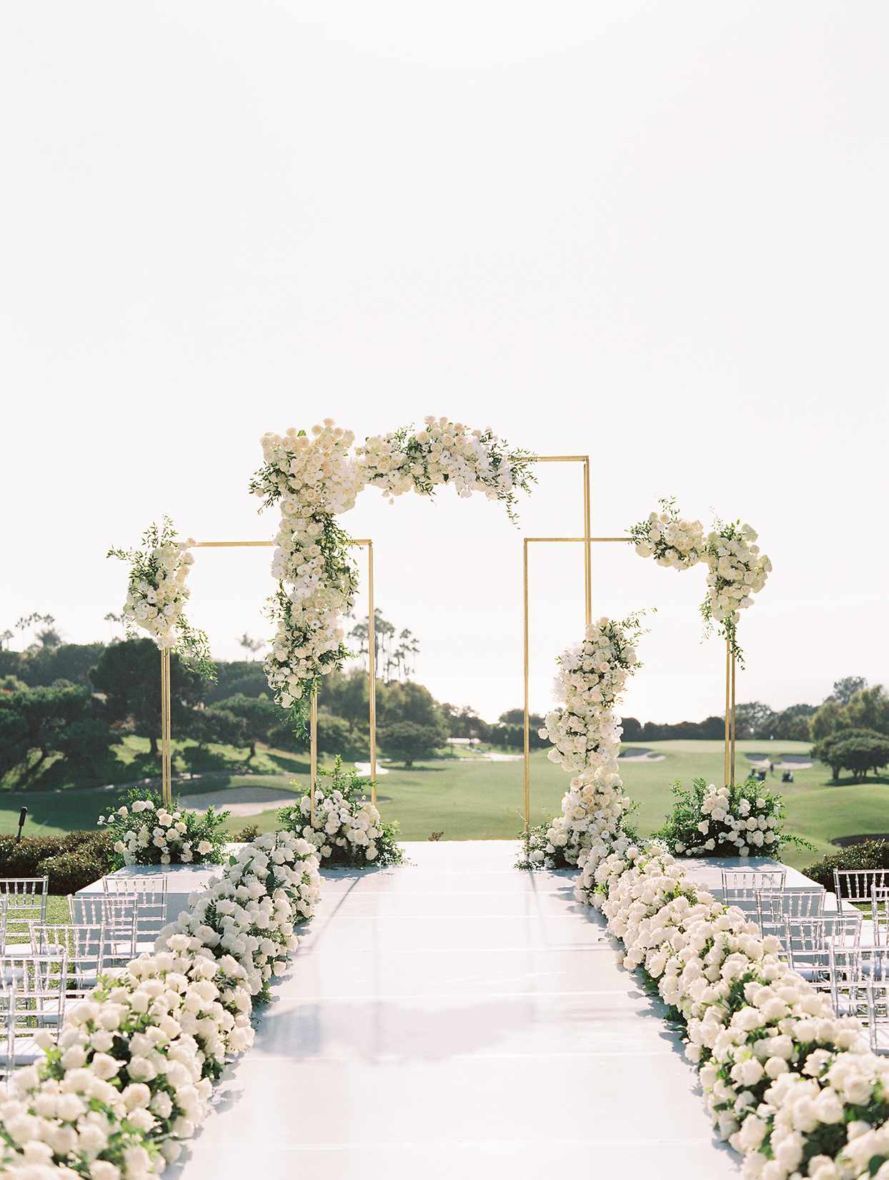 outdoor wedding ceremony with white catwalk lined with white roses