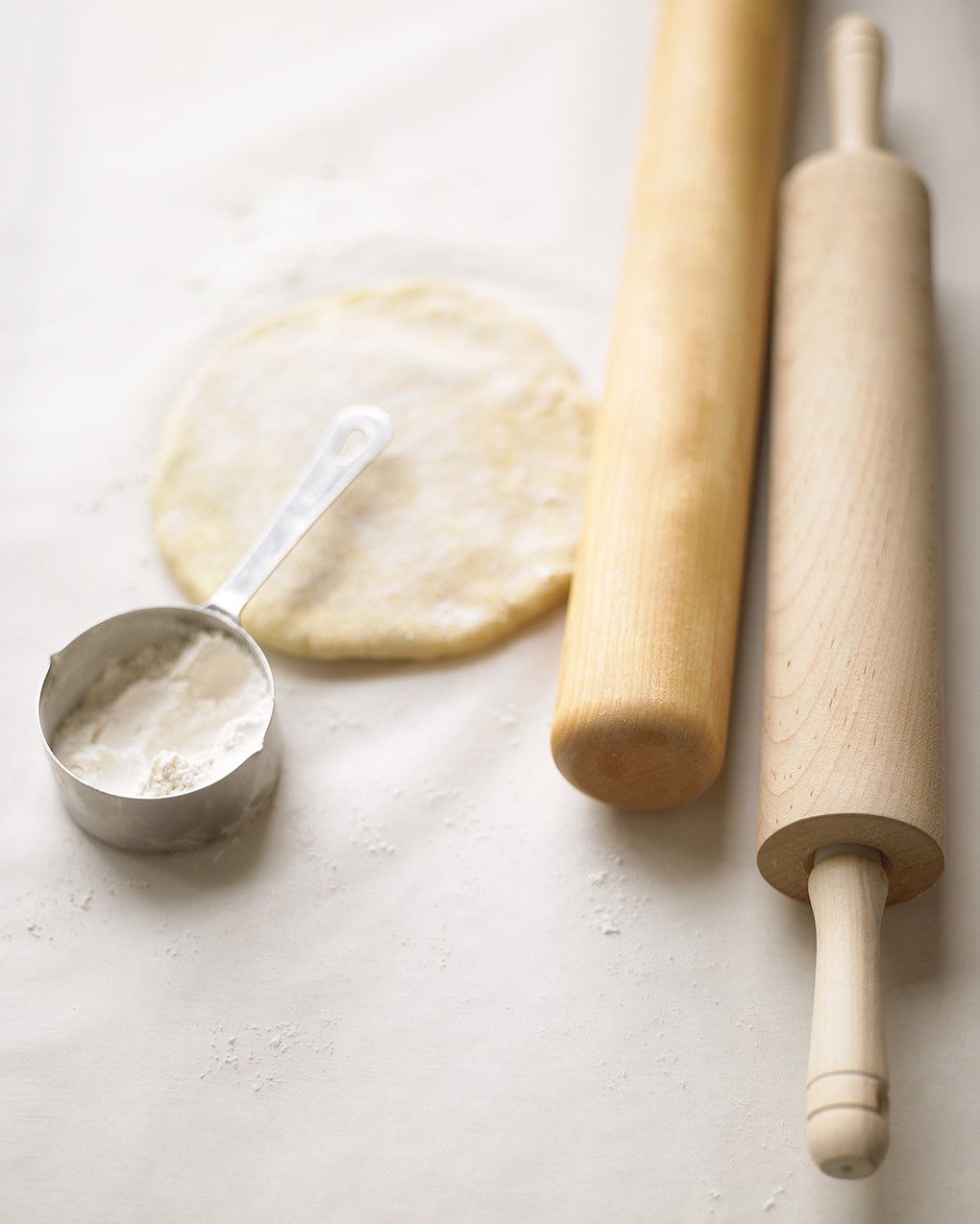 Wooden rolling pins and pie dough on floured surface