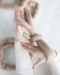 yarn looped around wrists and hands for arm knit blanket