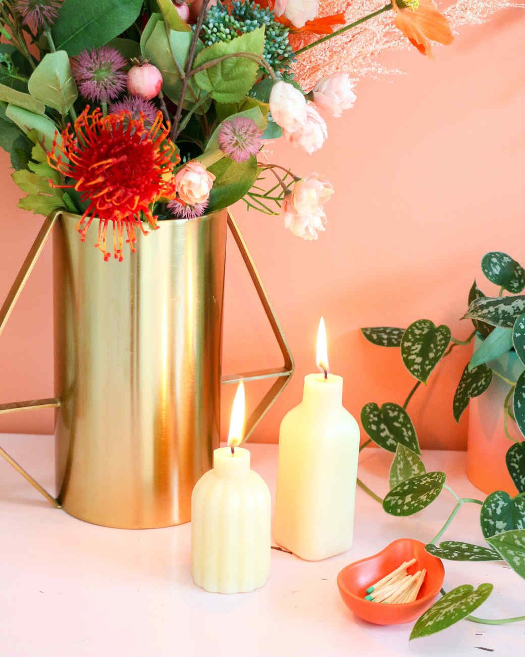 two white bottle candles lit and vase of flowers