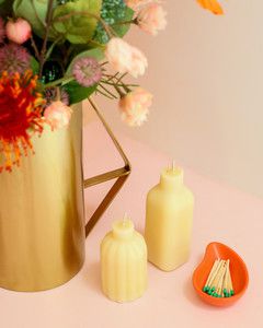 two white bottle candles and vase of flowers