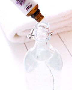 pouring oil into a glass bottle of fabric softener