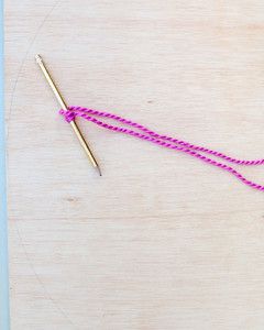 pink yarn tied around gold pencil