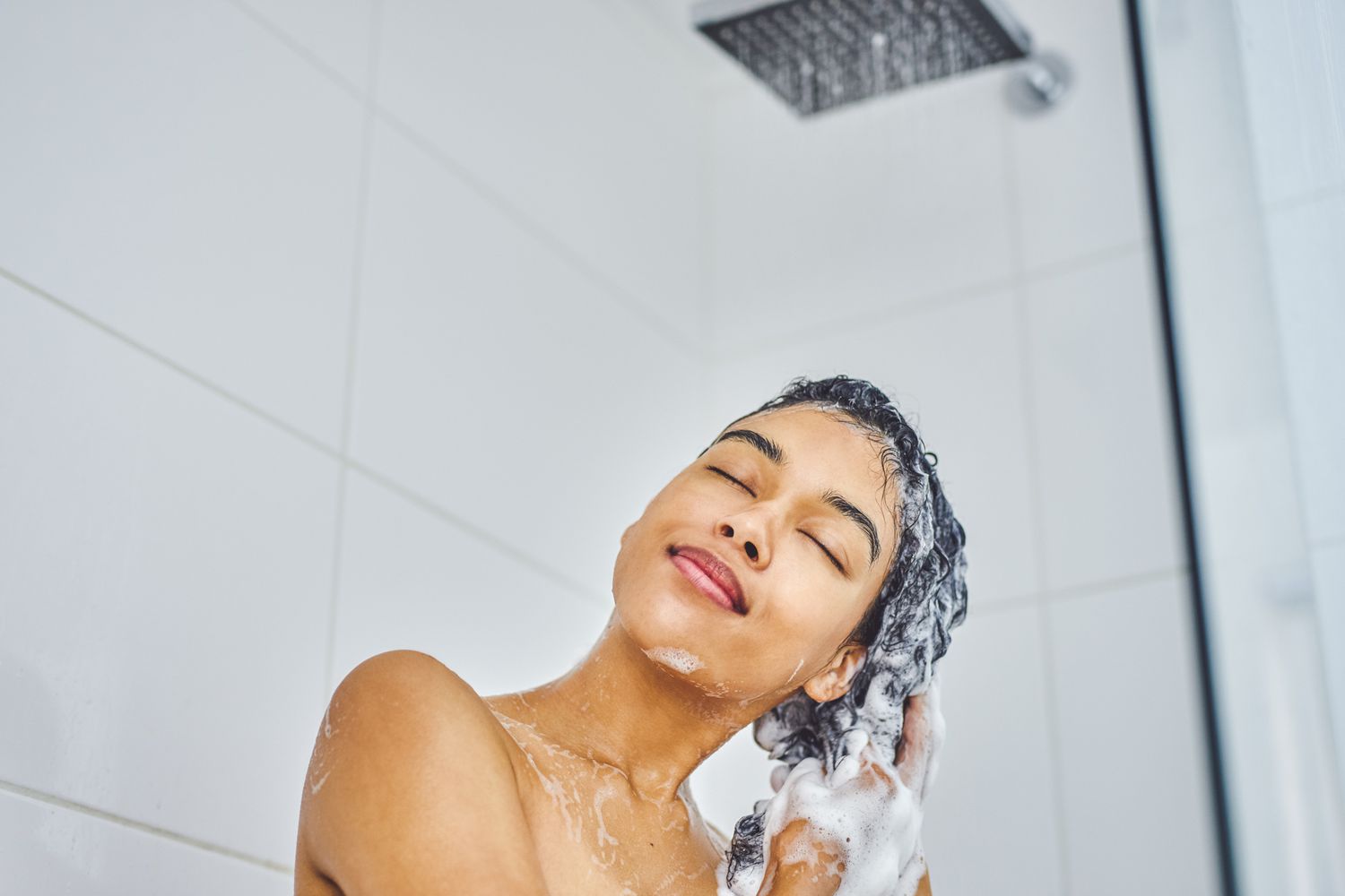 person washing hair in shower under running water