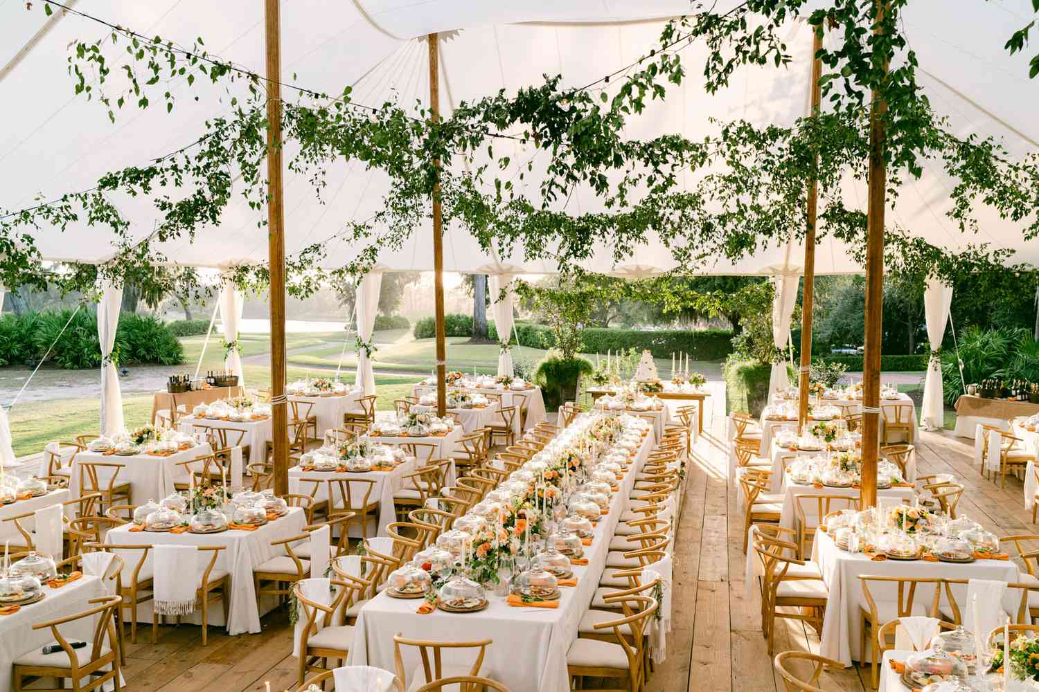 elegant tent wedding reception with orange and wooden decor