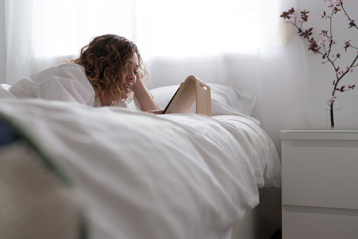 woman laying in bed looking at ipad