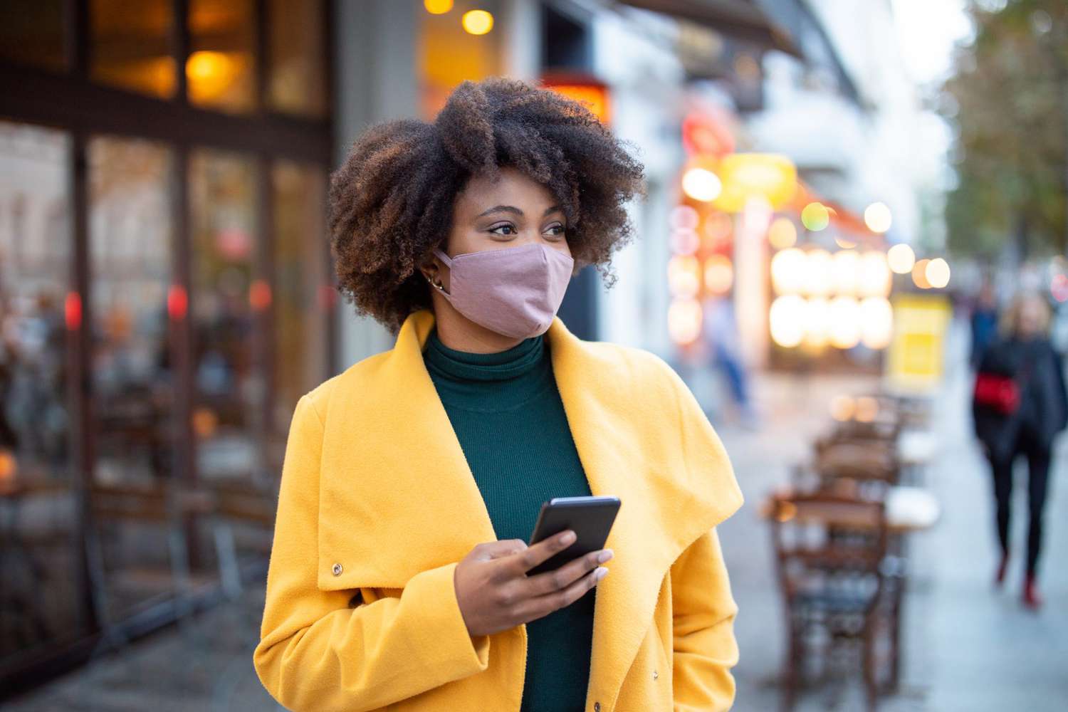 Woman in the city wearing face mask and holding cell phone