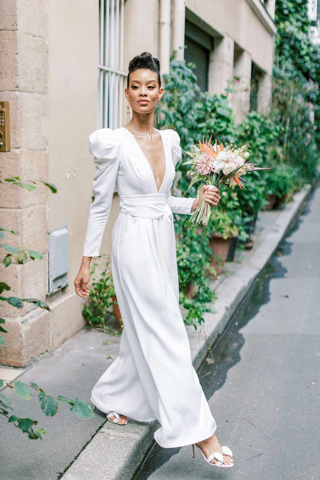 bride in long sleeve dress walking with bouquet