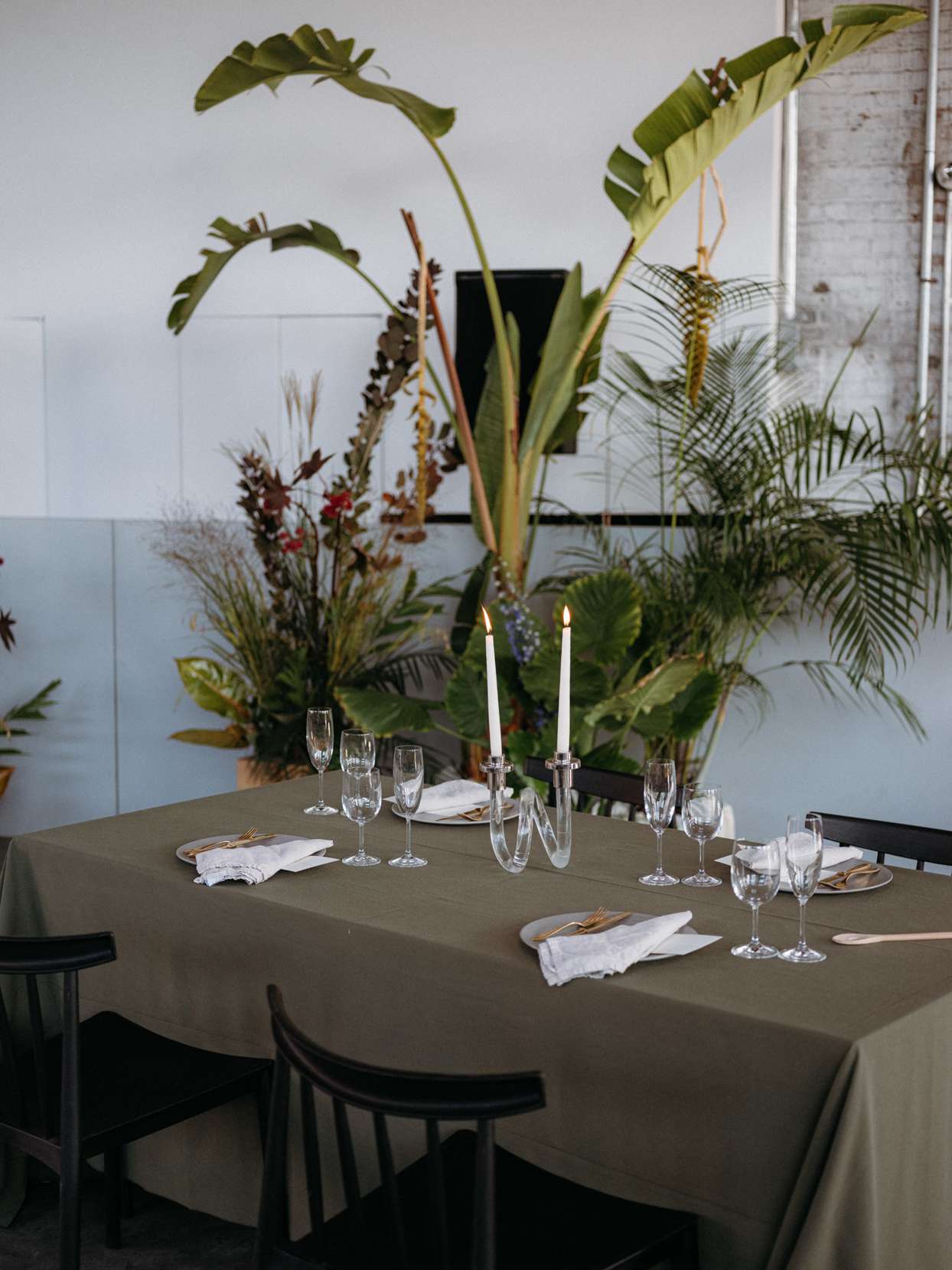 simple wedding reception table with two candles and tropical plants backdrop