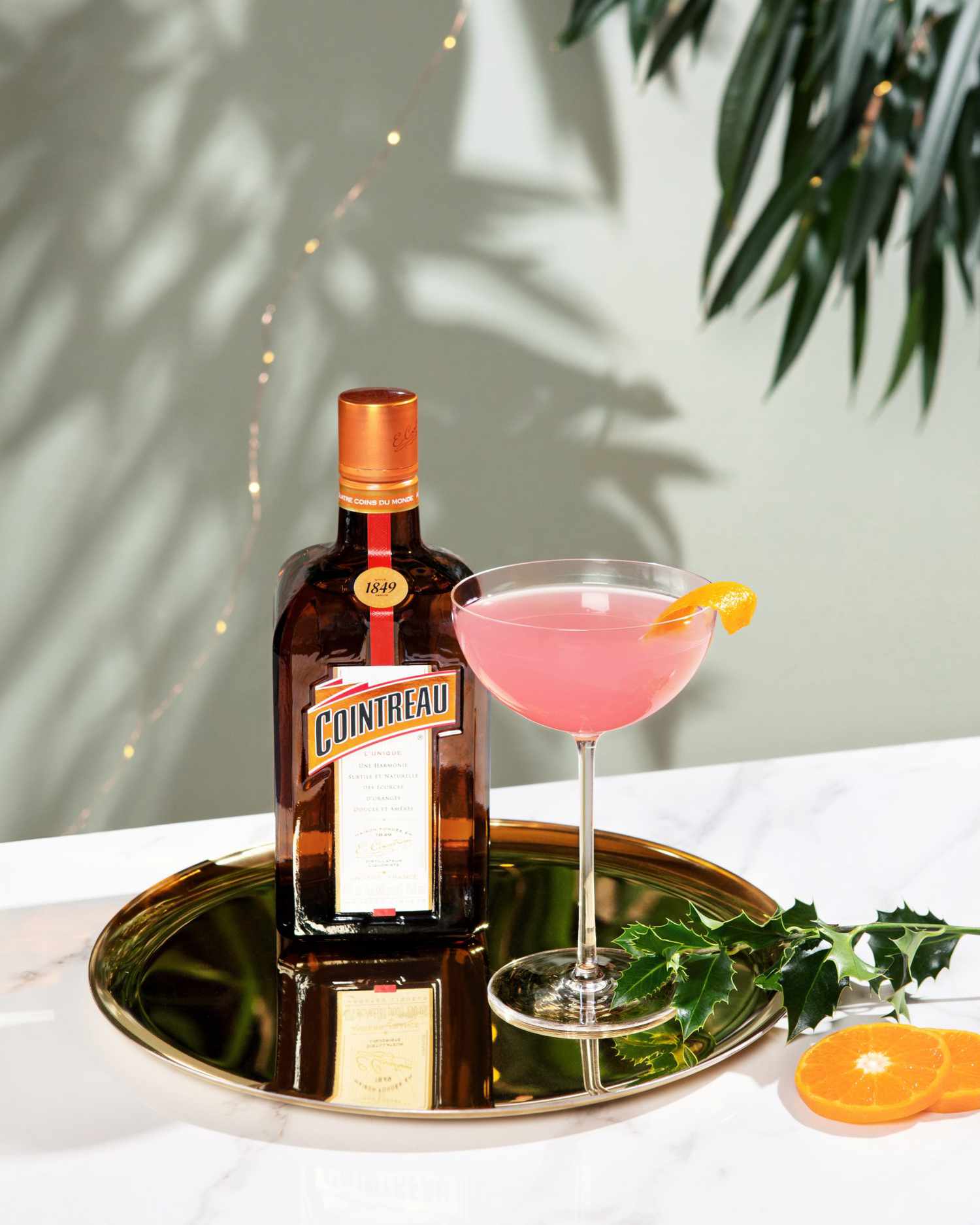 bottle of Cointreau and glass with pink cocktail on brass tray