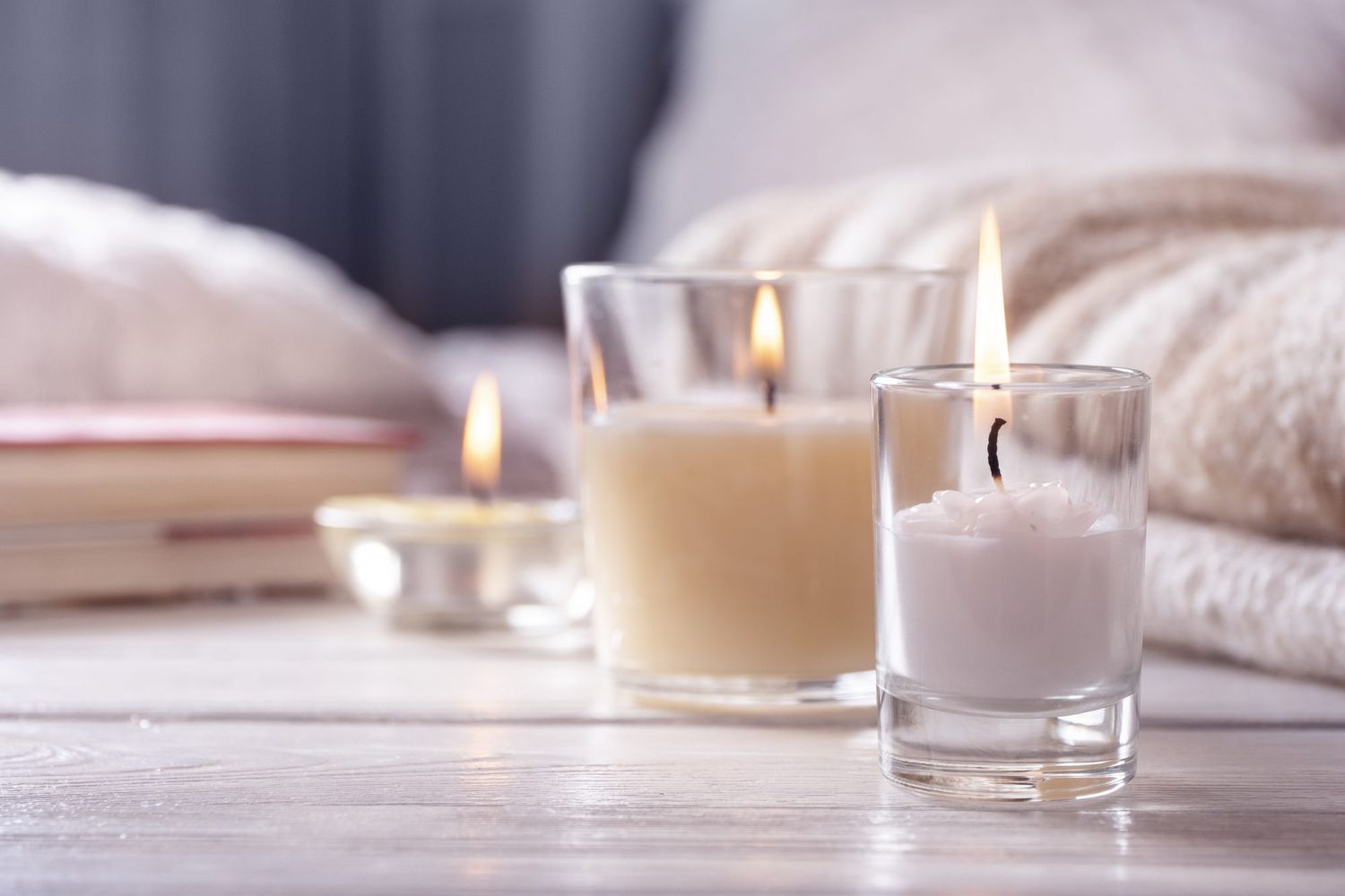 several candles on white wooden table in front of bed