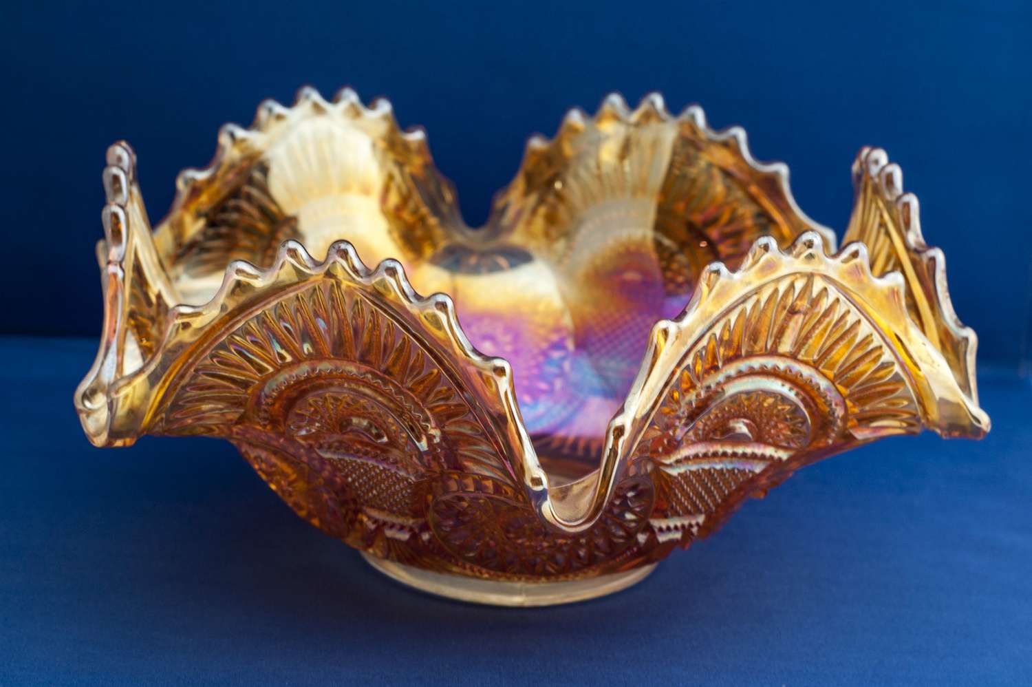 yellow carnival glass bowl on blue surfacce
