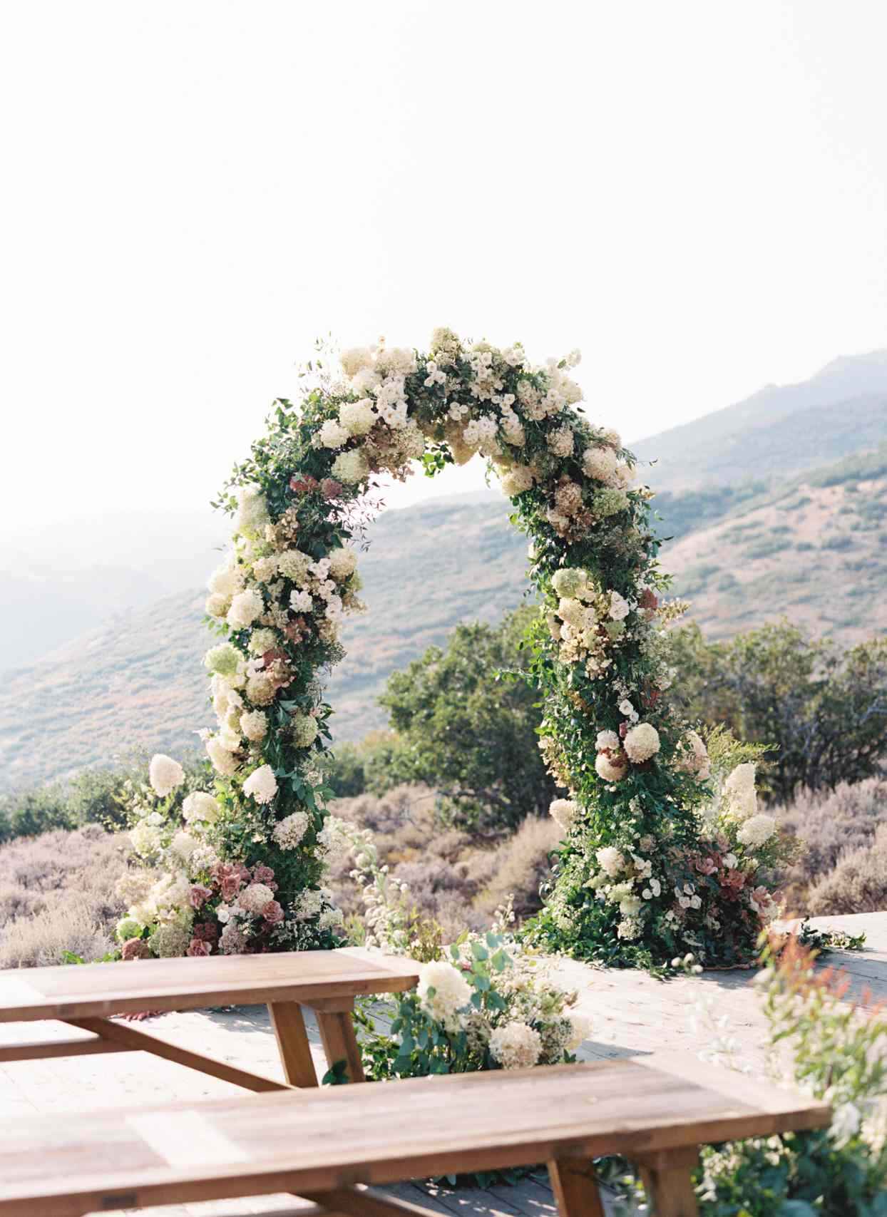 large floral wedding arch on hillside