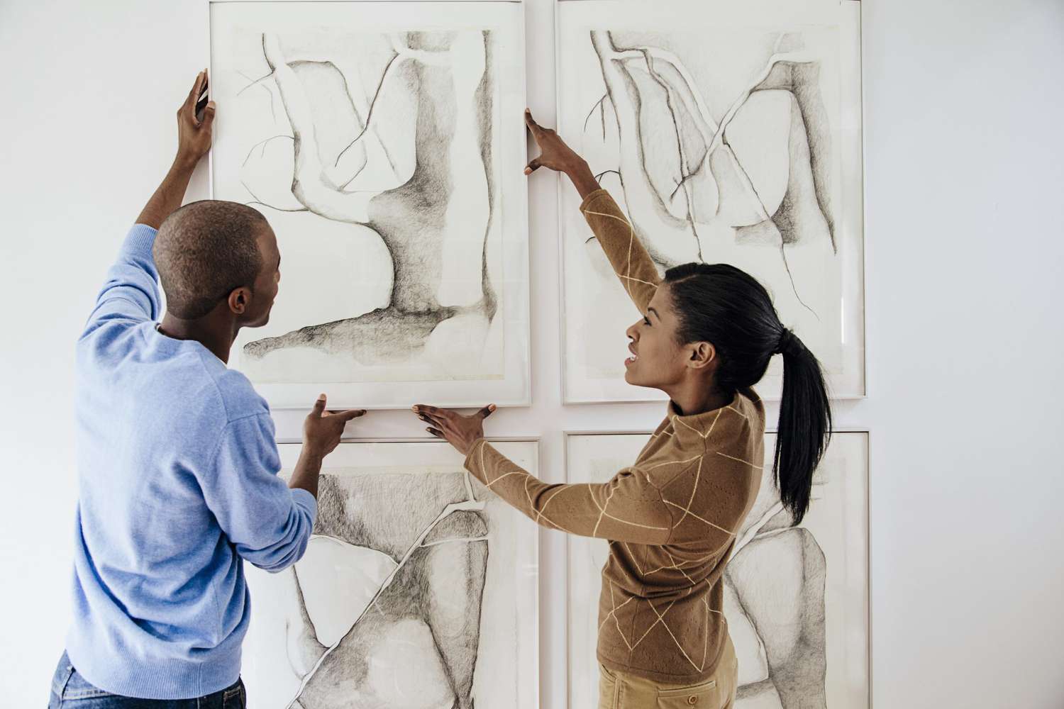 young couple hanging large art on wall