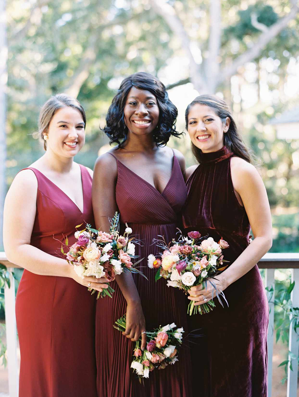 bridesmaids in burgundy dresses with floral bouquets