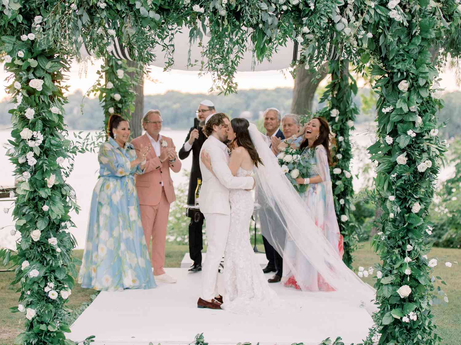 bride and groom kissing beneath floral chuppah wedding ceremony