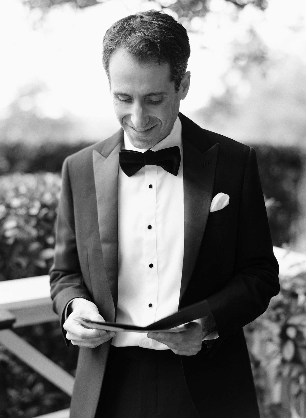 groom wearing tux reading card