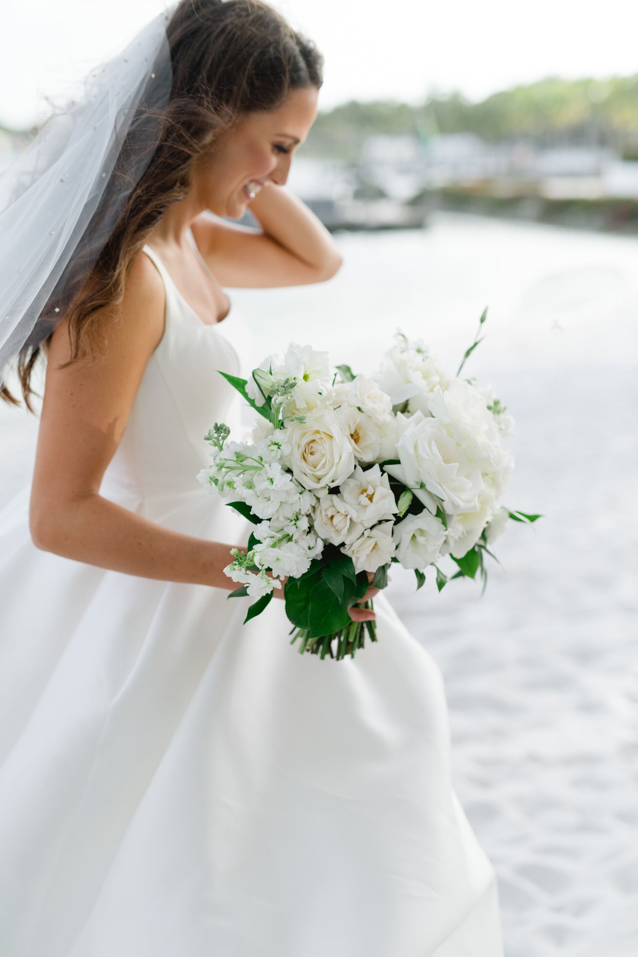 bride running on beach holding white wedding flowers
