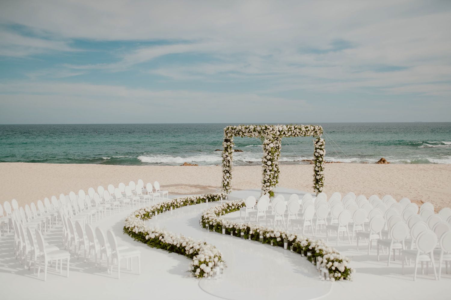 elegant curved white wedding ceremony setting on beach