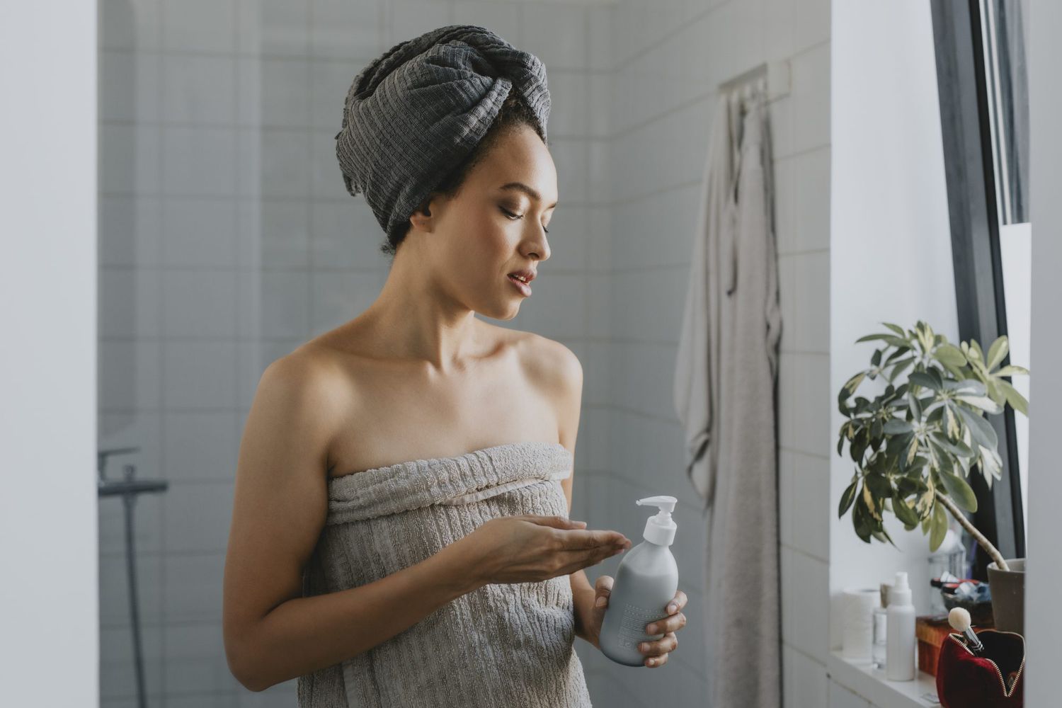 woman in bath towel applying cream to hand