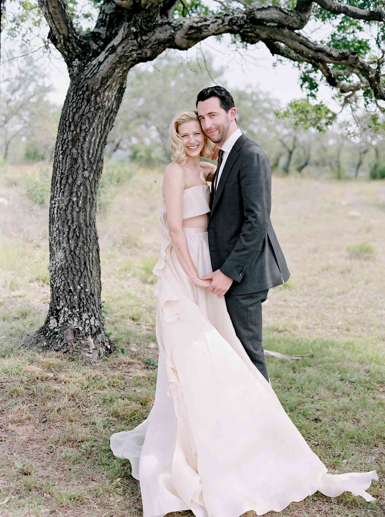 bride and groom posing under tree
