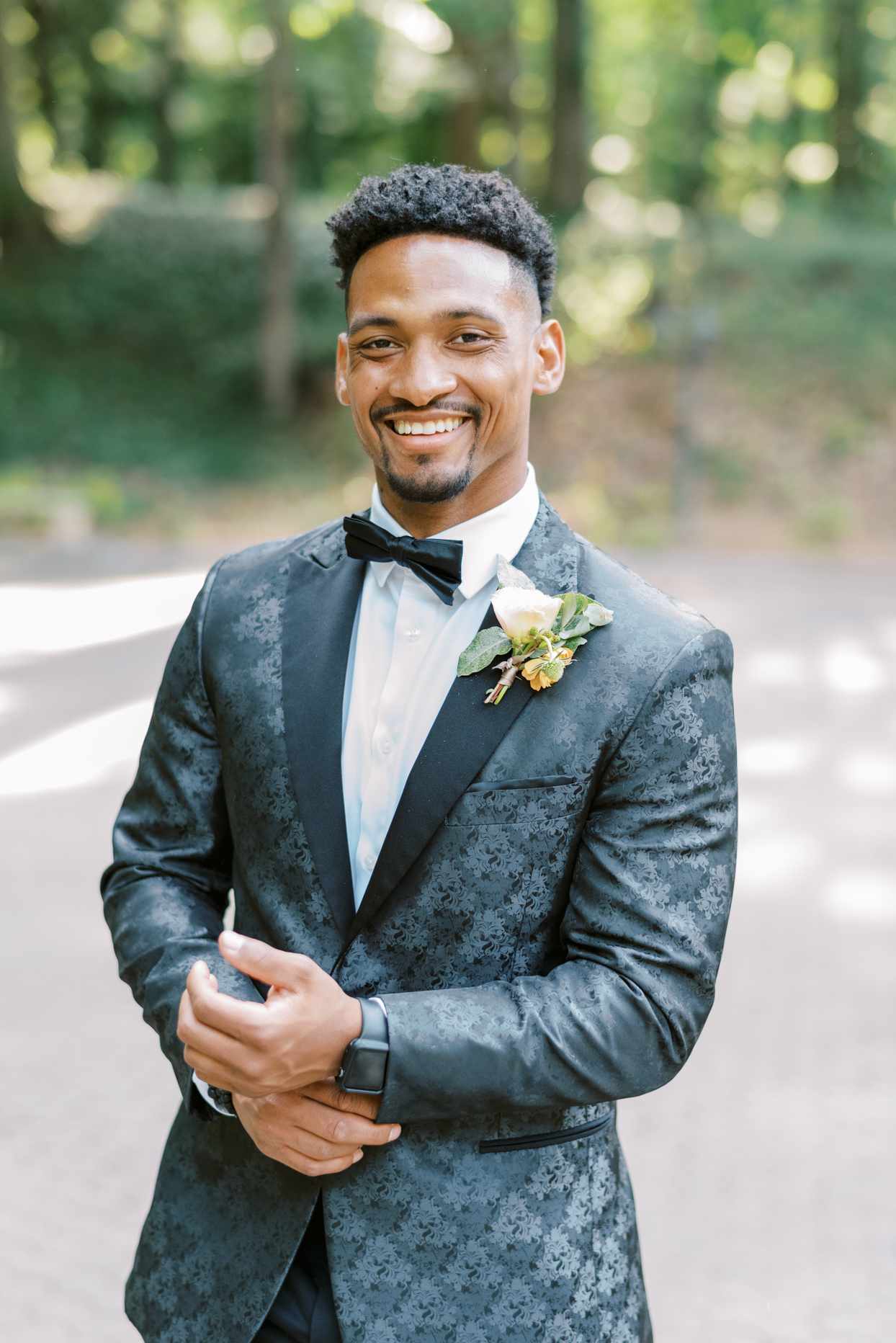 groom smiling wearing custom black and gray tux