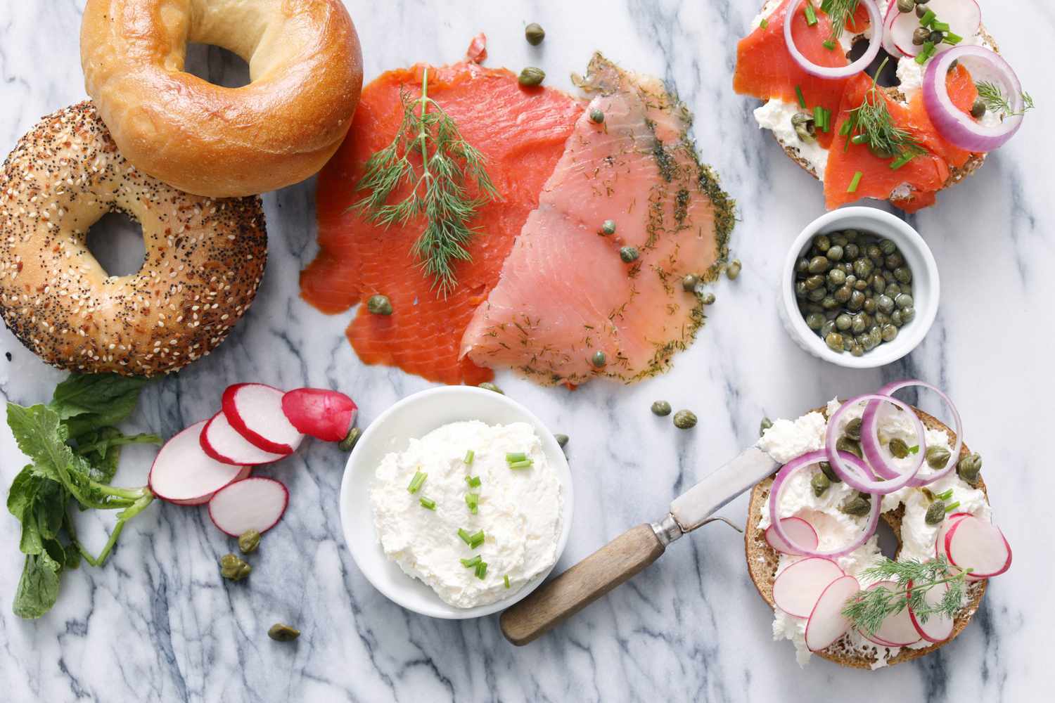 bagels and smoked salmon spread on marble counter