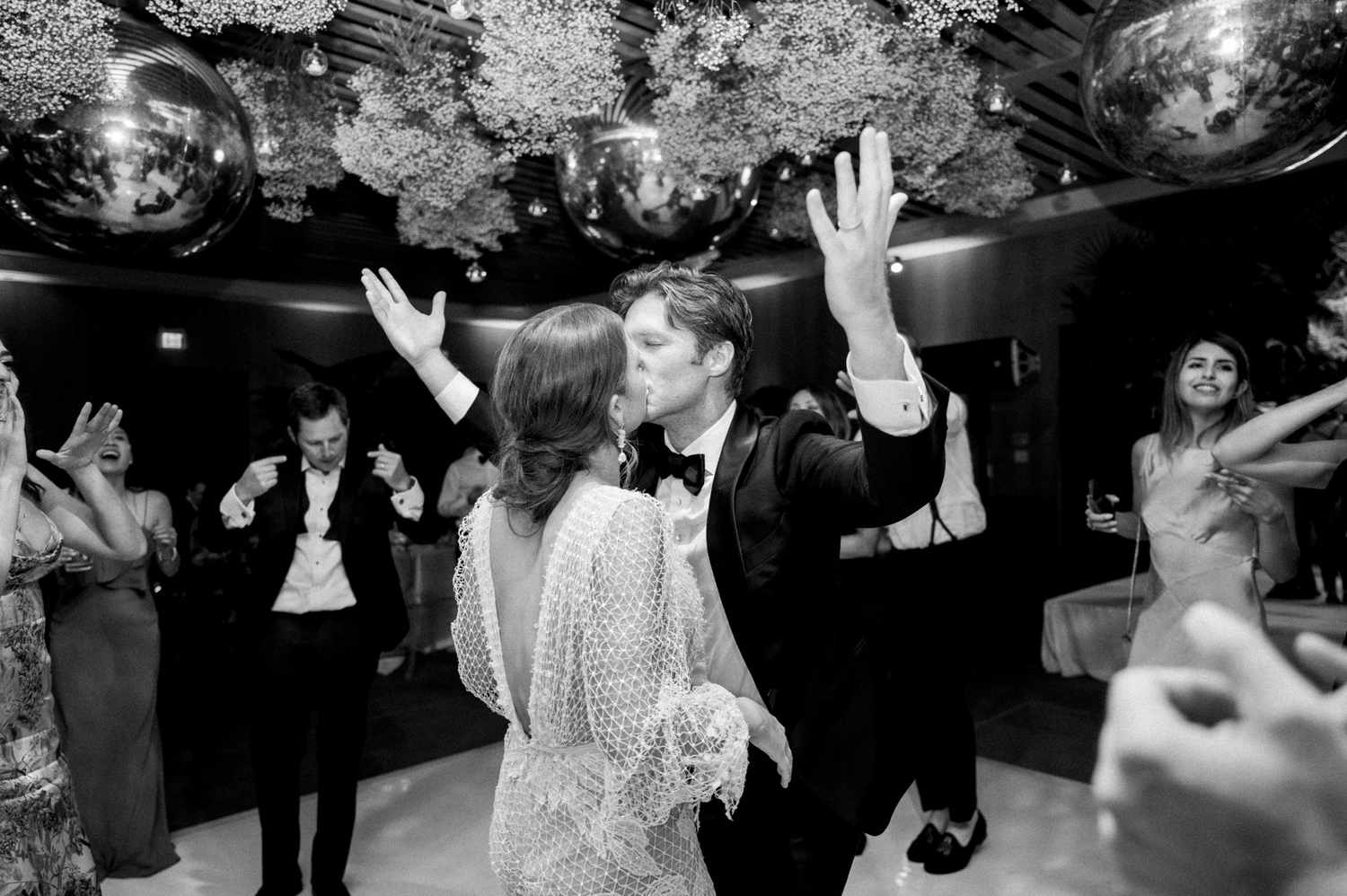 bride and groom share a kiss during dance surrounded by guests