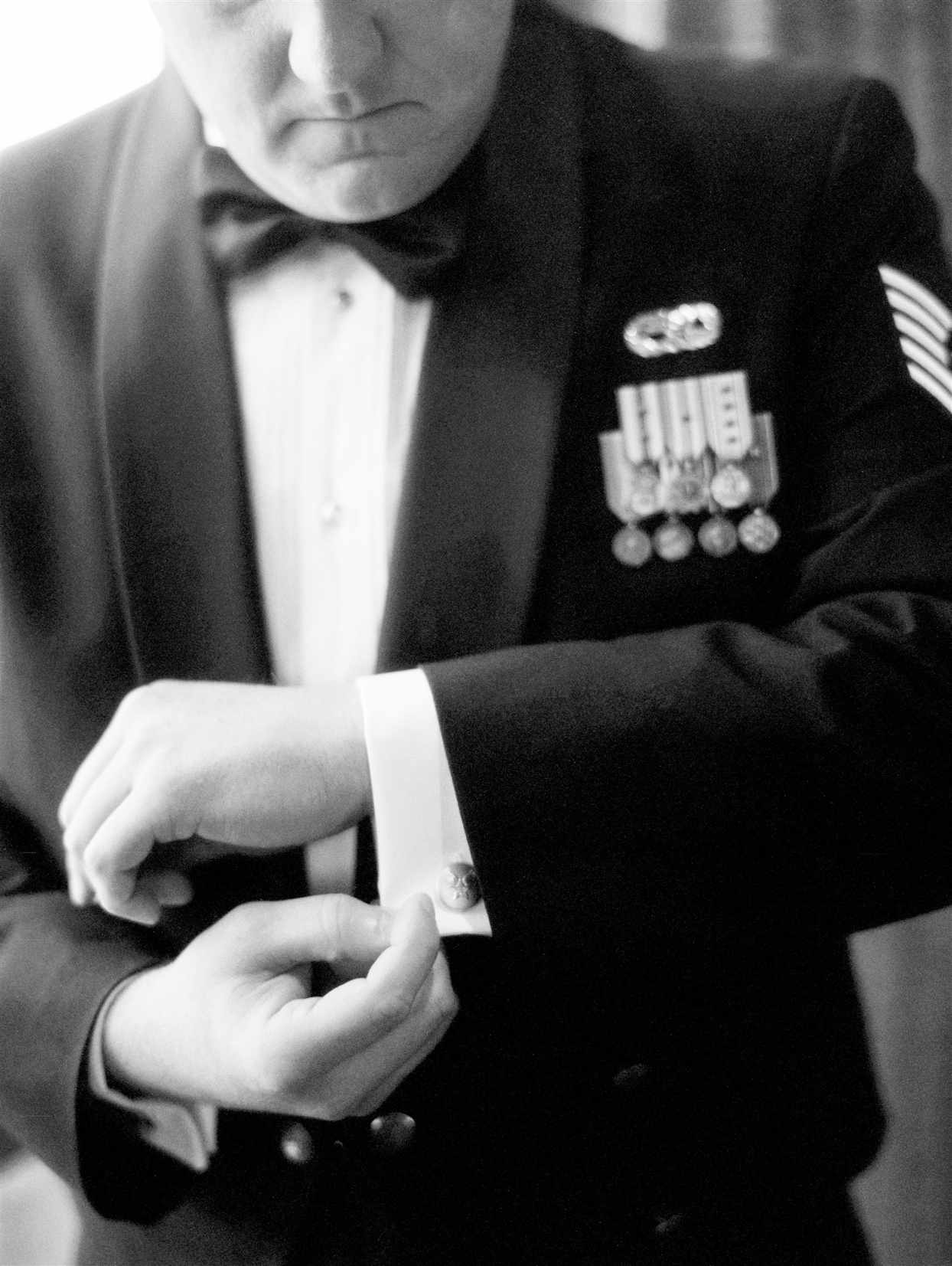 groom wearing uniform suit buttoning his sleeve