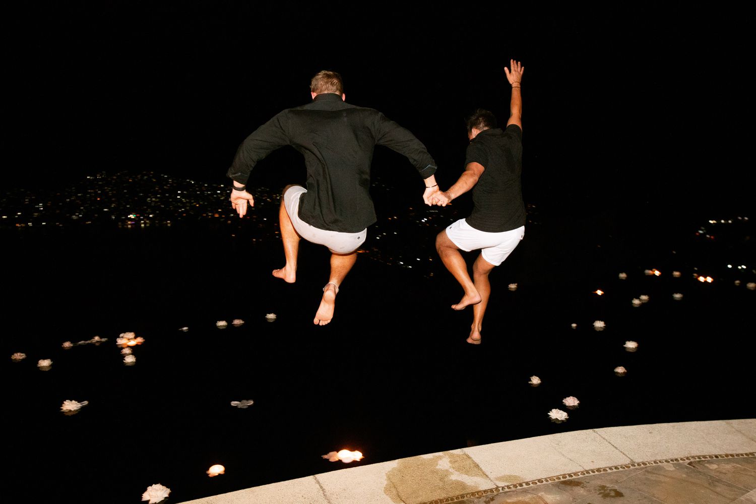 grooms jumping into pool holding hands