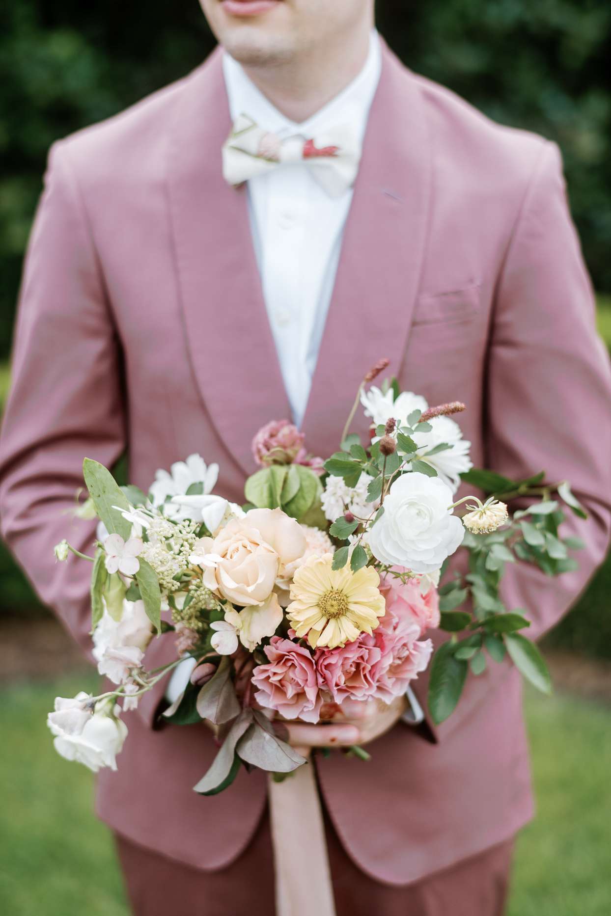 bridesman in pink suit holding flowers