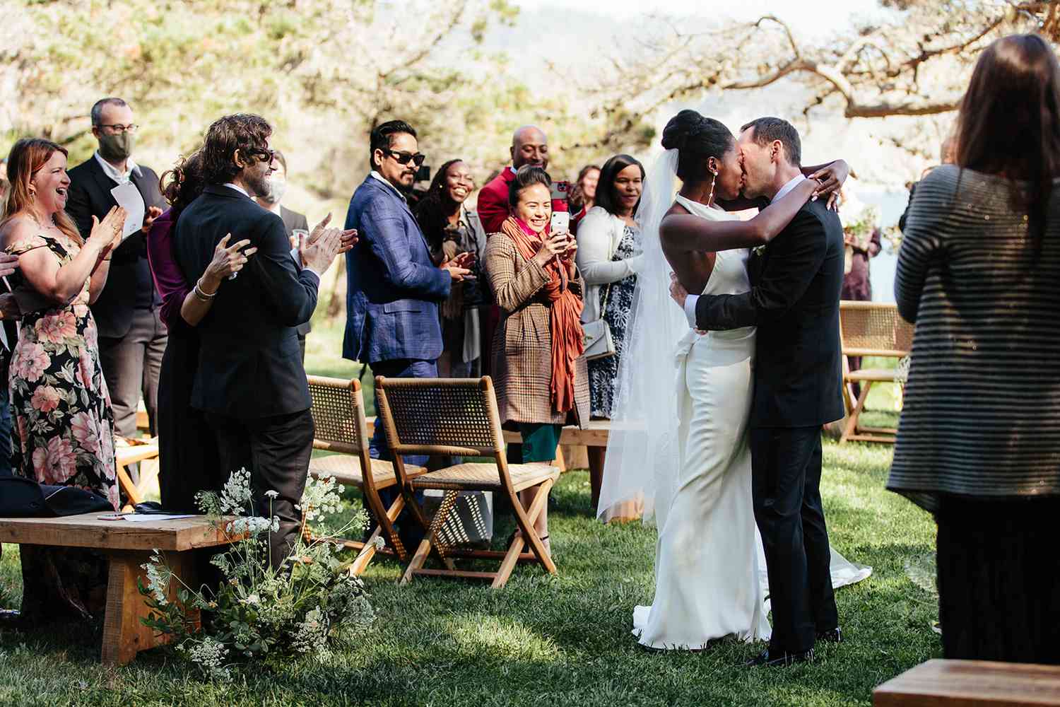 在婚礼上，新娘和新郎在宾客的簇拥下接吻